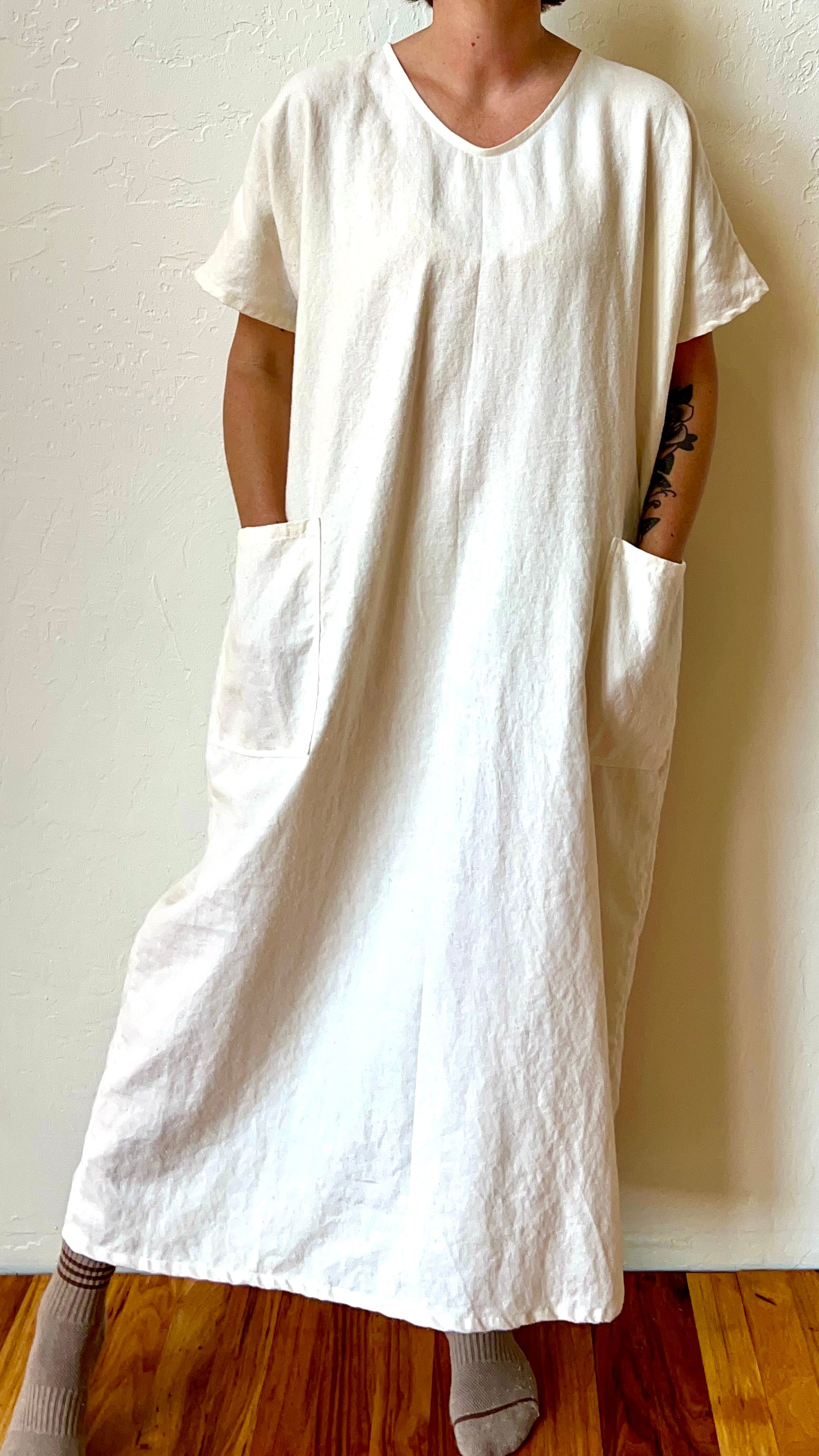 Person wearing a white organic hemp kaftan dress against a plain background
