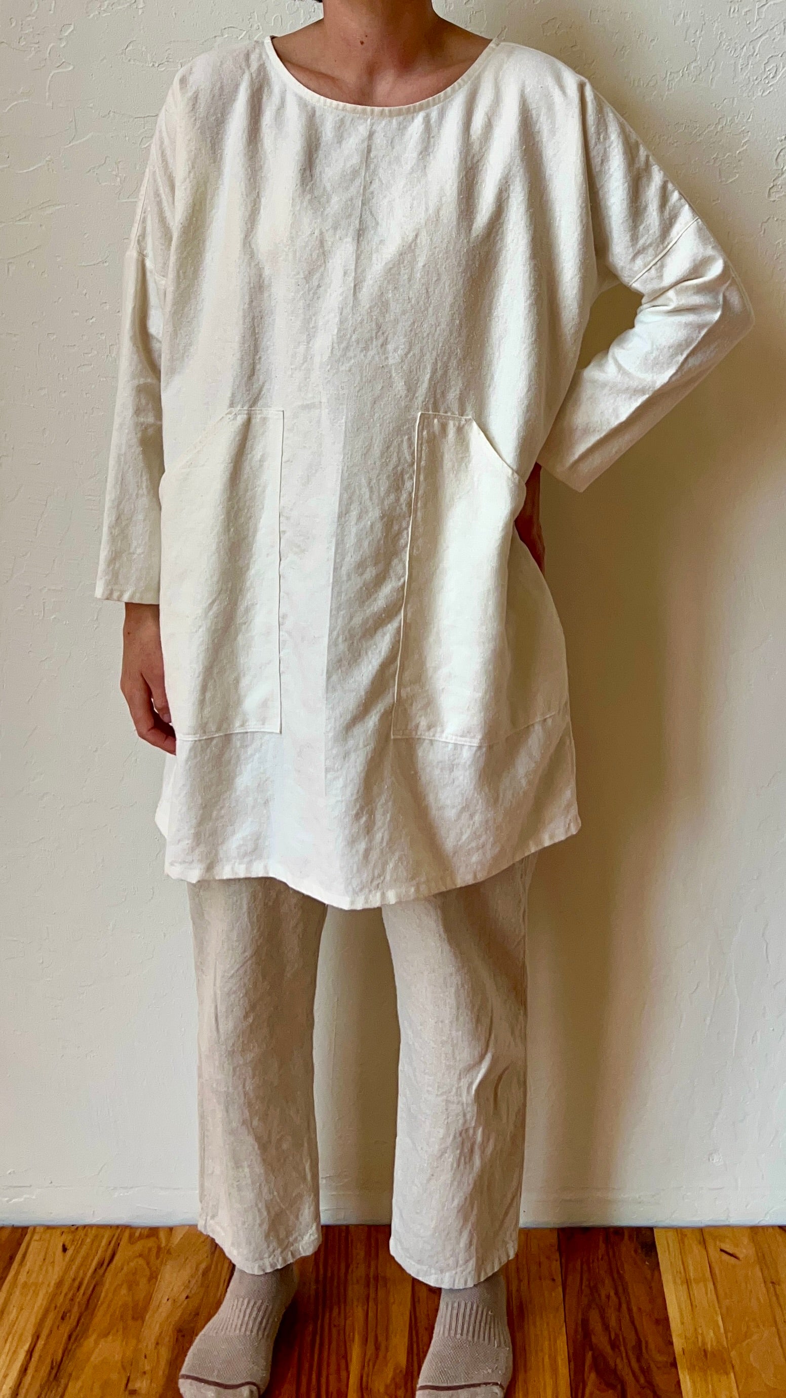 Person wearing a white organic hemp tunic with big pockets. 