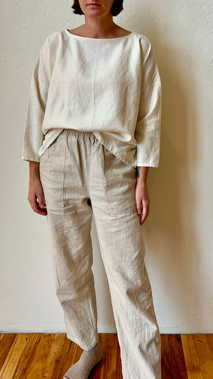 Person wearing a white hemp outfit against a plain wall