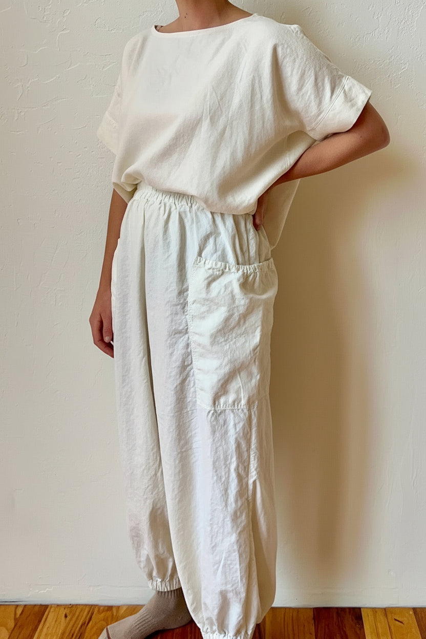 Person wearing a white hemp outfit standing against a plain wall.